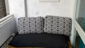 A wooden bench with black and white patterned cushions, a framed cactus artwork on the wall, and a window with a view. - Vacation Studio 'Puerto Centro House' with Balcony and Wi-Fi (Puerto de la Cruz)
