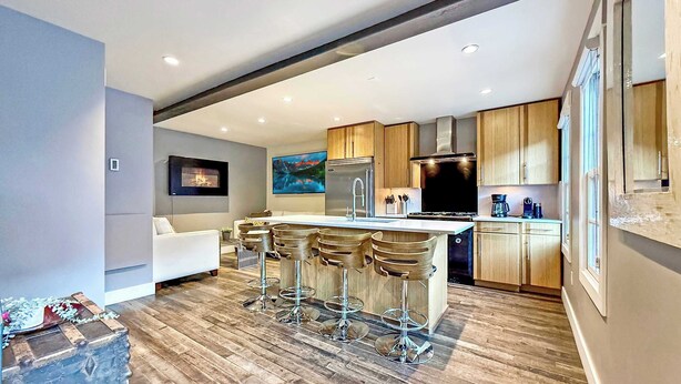 A modern kitchen with a central island, bar stools, a built-in oven, and a large window. - A romantic getaway that's steps from Main Street. (Park City)