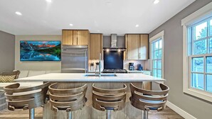 A modern kitchen with a central island, stainless steel appliances, and wooden bar stools. - A romantic getaway that's steps from Main Street. (Park City)