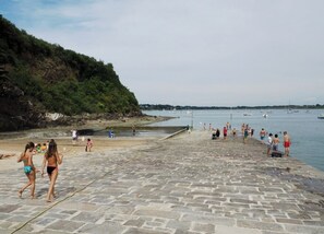 Eine gepflasterte Uferpromenade mit Menschen, die dort entlanggehen und am Wasser stehen.
