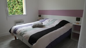 A bedroom with a bed, nightstands, a window, and a view of greenery outside. - Cap Rance With family and friends! (Plouër-sur-Rance)