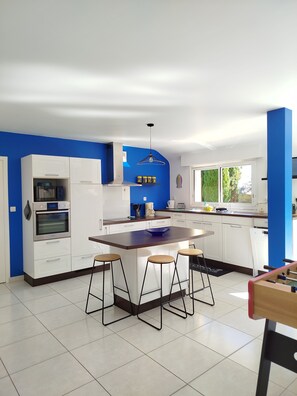 Una cocina moderna con armarios blancos, una isla central con taburetes y una pared de acento azul.