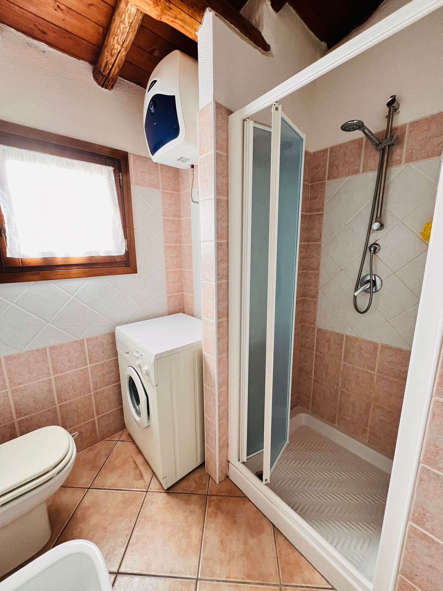 Un baño pequeño con lavadora, inodoro y cabina de ducha.