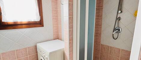 Un baño pequeño con lavadora, inodoro y cabina de ducha.