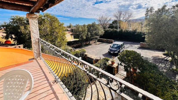 Ein Balkon mit Blick auf einen Parkplatz und umgebende Grünflächen.