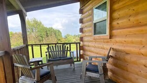 A wooden cabin with a porch featuring two Adirondack chairs and a small table. - Relax & Recharge at Firefly Cabin (Russellville)