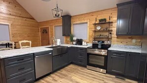 A kitchen with dark cabinets, stainless steel appliances, and a wooden floor. - Relax & Recharge at Firefly Cabin (Russellville)