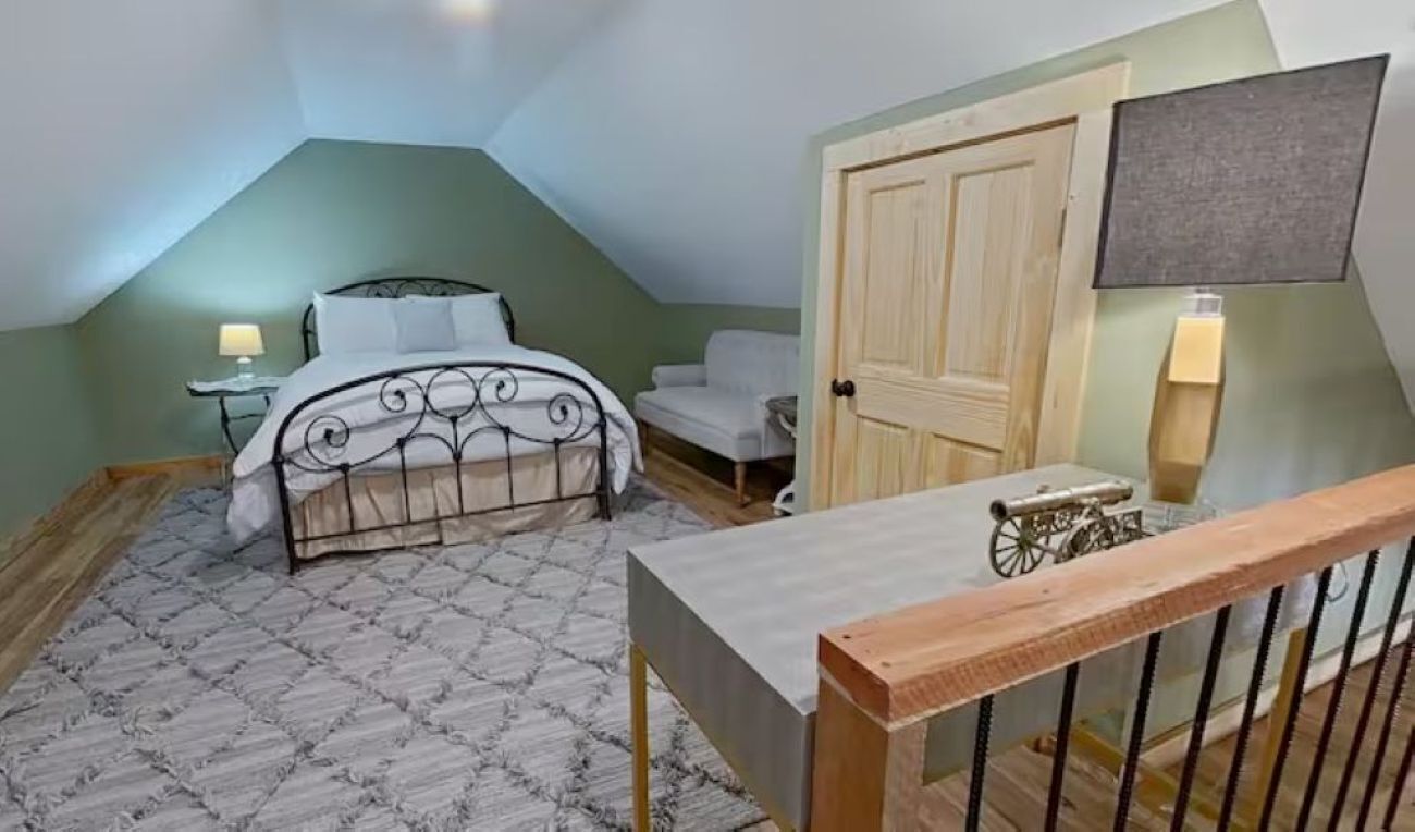 A bedroom with a bed, bedside table, lamp, and a door.