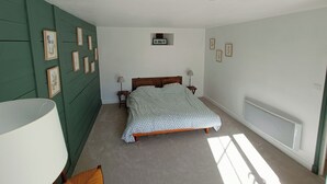 Une chambre à coucher comprenant un lit, deux tables de chevet, un radiateur fixé au mur et des tableaux encadrés accrochés au mur.