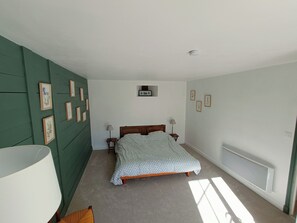 A bedroom with a bed, two bedside tables, a wall-mounted heater, and framed pictures on the wall. - Typical house with private pool - 6km Sarlat (Saint-André-d'Allas)