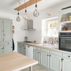 A kitchen with white cabinetry, a wooden table, a stove, a dishwasher, and hanging light fixtures. - Typical house with private pool - 6km Sarlat (Saint-André-d'Allas)