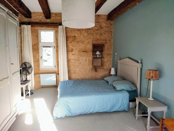 Une chambre à coucher avec un lit, un ventilateur, une lampe et une fenêtre.