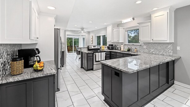 A modern kitchen with dark cabinets, a granite countertop, and a central island. - Lake Retreat w/ Hot Tub, Game Room & Grill (Rogers)