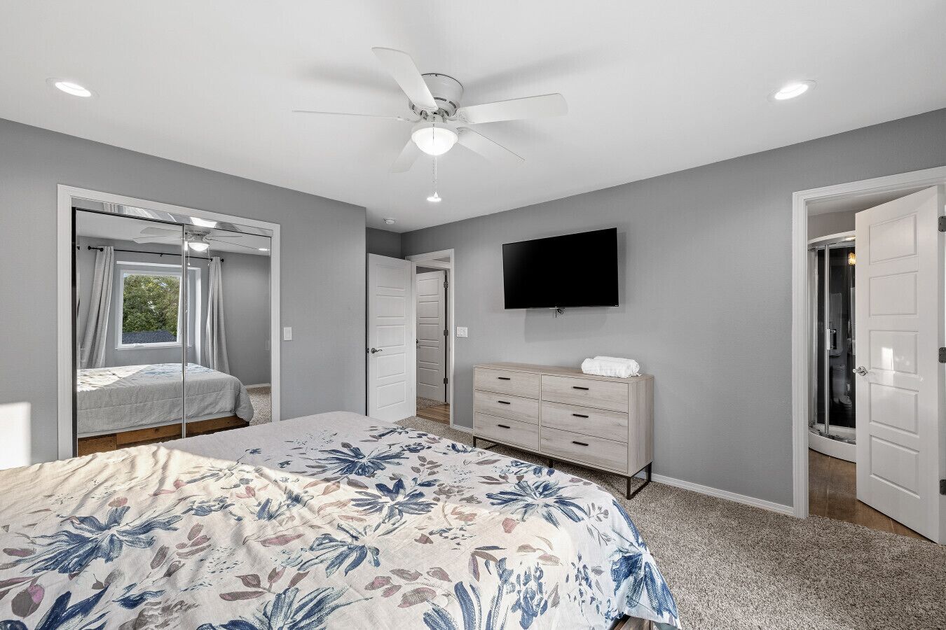 Un dormitorio con cama, cómoda, ventilador de techo y televisor.