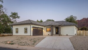 A single-story house with a garage, a front porch, and a driveway leading to the entrance. - Game room+Hot tub+Mtn views+Parking+Kid-friendly (Moab)