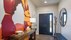 A hallway with a wooden bench, a door, a mirror, and a wall with a colorful abstract painting. - Game room+Hot tub+Mtn views+Parking+Kid-friendly (Moab)
