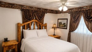 Une chambre à coucher avec un lit en bois, une table de chevet, une lampe, un ventilateur de plafond et un tableau encadré au mur.