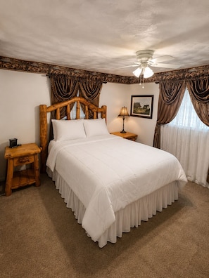 A bedroom with a wooden bed, a nightstand, a lamp, a ceiling fan, and a framed picture on the wall. - Relaxing Escape - Private Pool  (Silsbee)