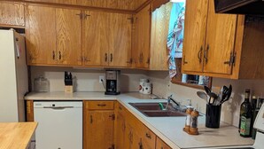Une cuisine avec des meubles de rangement en bois, une machine à café, un évier et une cuisinière.