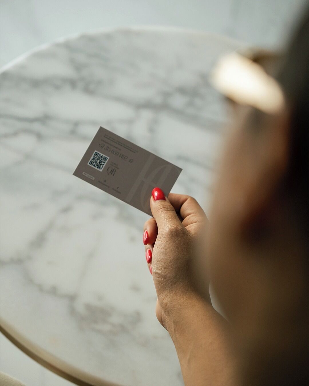 A person holding a business card with a QR code.