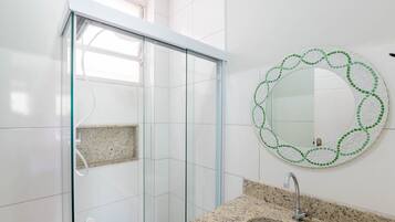 Un bagno moderno con box doccia in vetro, un piano di lavoro in granito e uno specchio decorato con mosaici.