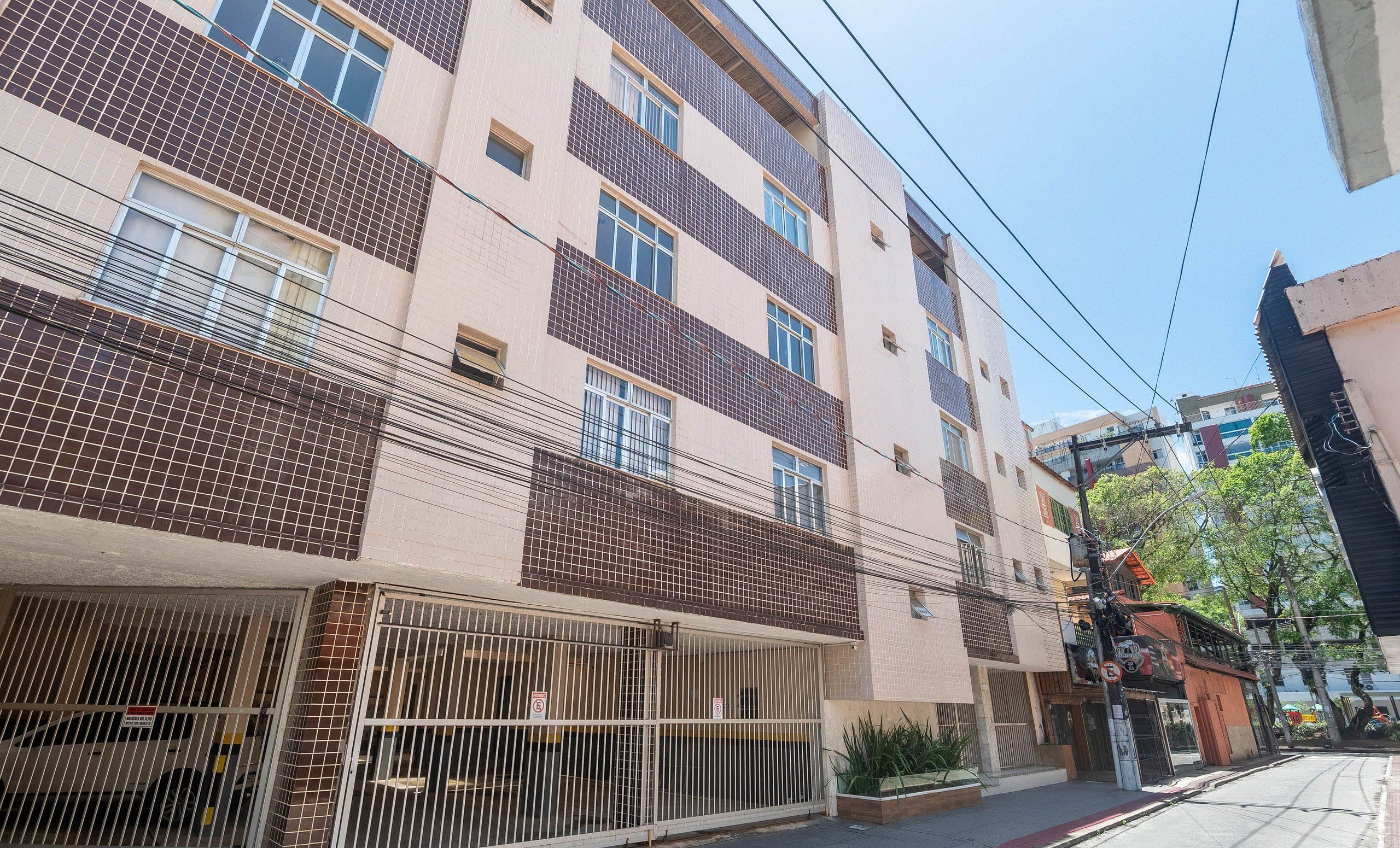 Un edificio residenziale a più piani con facciata in tegole, ingresso chiuso da cancello e un balcone visibile.