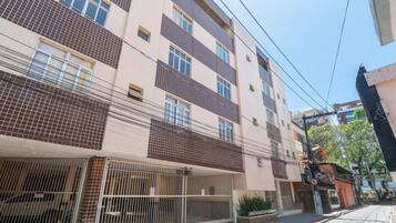 Un edificio residenziale a più piani con facciata in tegole, ingresso chiuso da cancello e un balcone visibile.