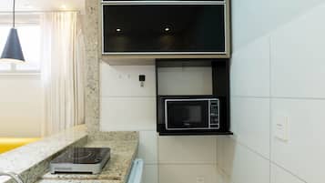 A compact kitchen with a built-in microwave, a countertop induction cooktop, and a small sink.