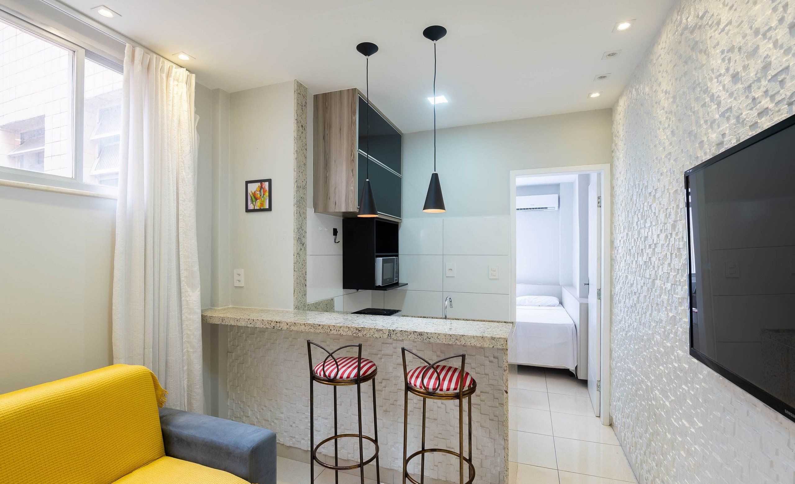A modern kitchen with a central island, bar stools, and pendant lighting.