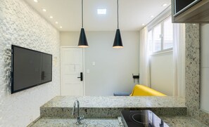 Une cuisine moderne dotée de plans de travail en granit, d’une cuisinière encastrée et de luminaires suspendus.