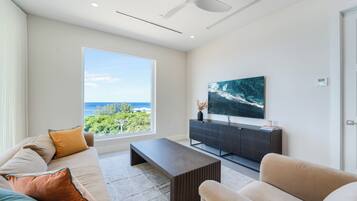 A modern living room with a large window, a flat-screen TV, and a minimalist design.