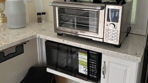 A compact kitchen with a built-in microwave, toaster oven, and a small trash bin. - Beaufort Bunkhouse (Beaufort)