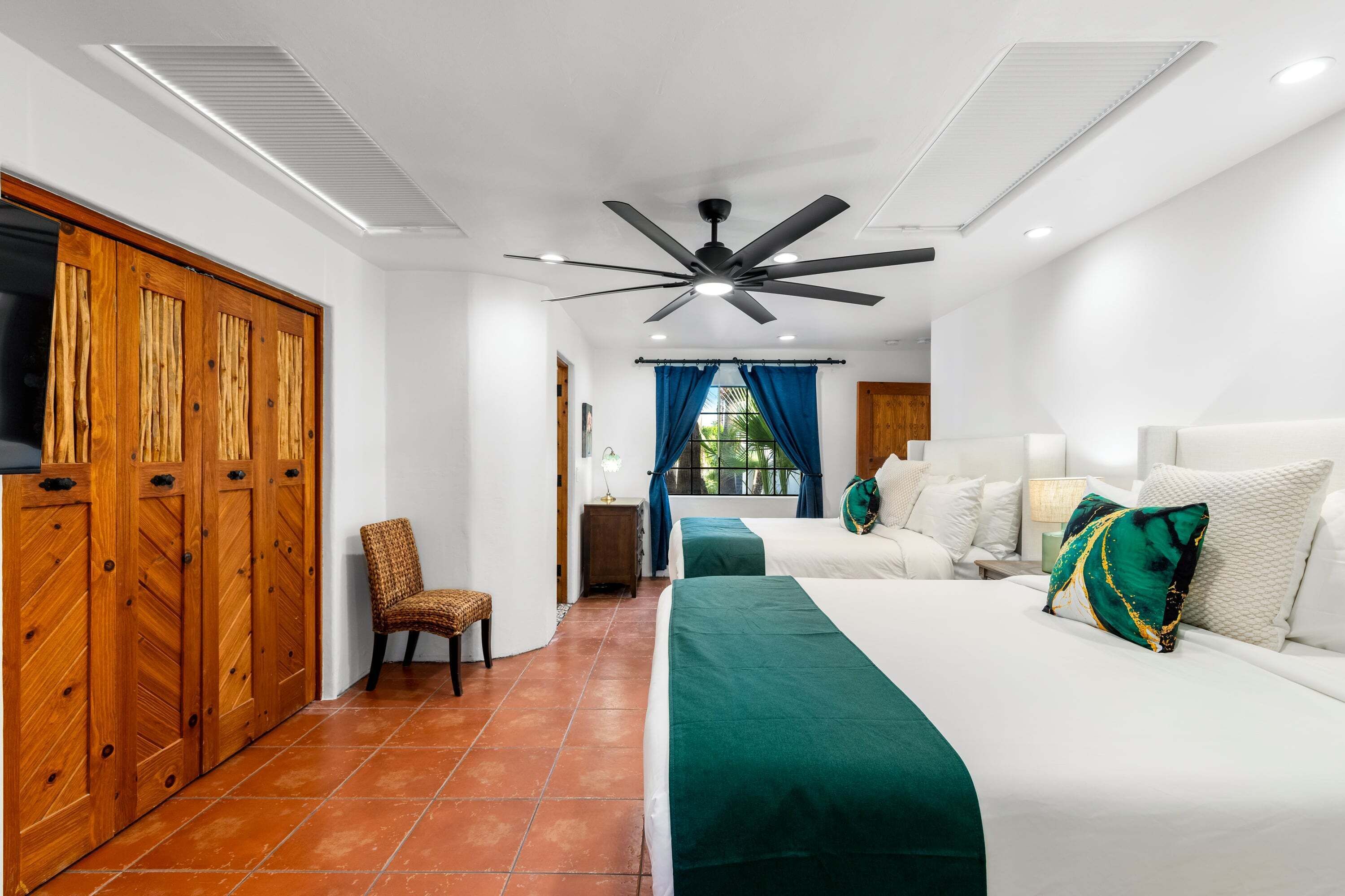 A bedroom with a bed, a chair, a wardrobe, and a ceiling fan.