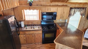 Una cocina compacta con armarios de madera, un refrigerador, una estufa, un microondas y un lavaplatos.
