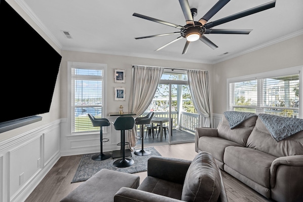 A living room with a ceiling fan, a sofa, a TV, and a dining area with a table and chairs.