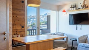 Ein modernes Wohnzimmer mit Holztisch, einer Couch, einer Bank und einem an der Wand befestigten Fernseher.
