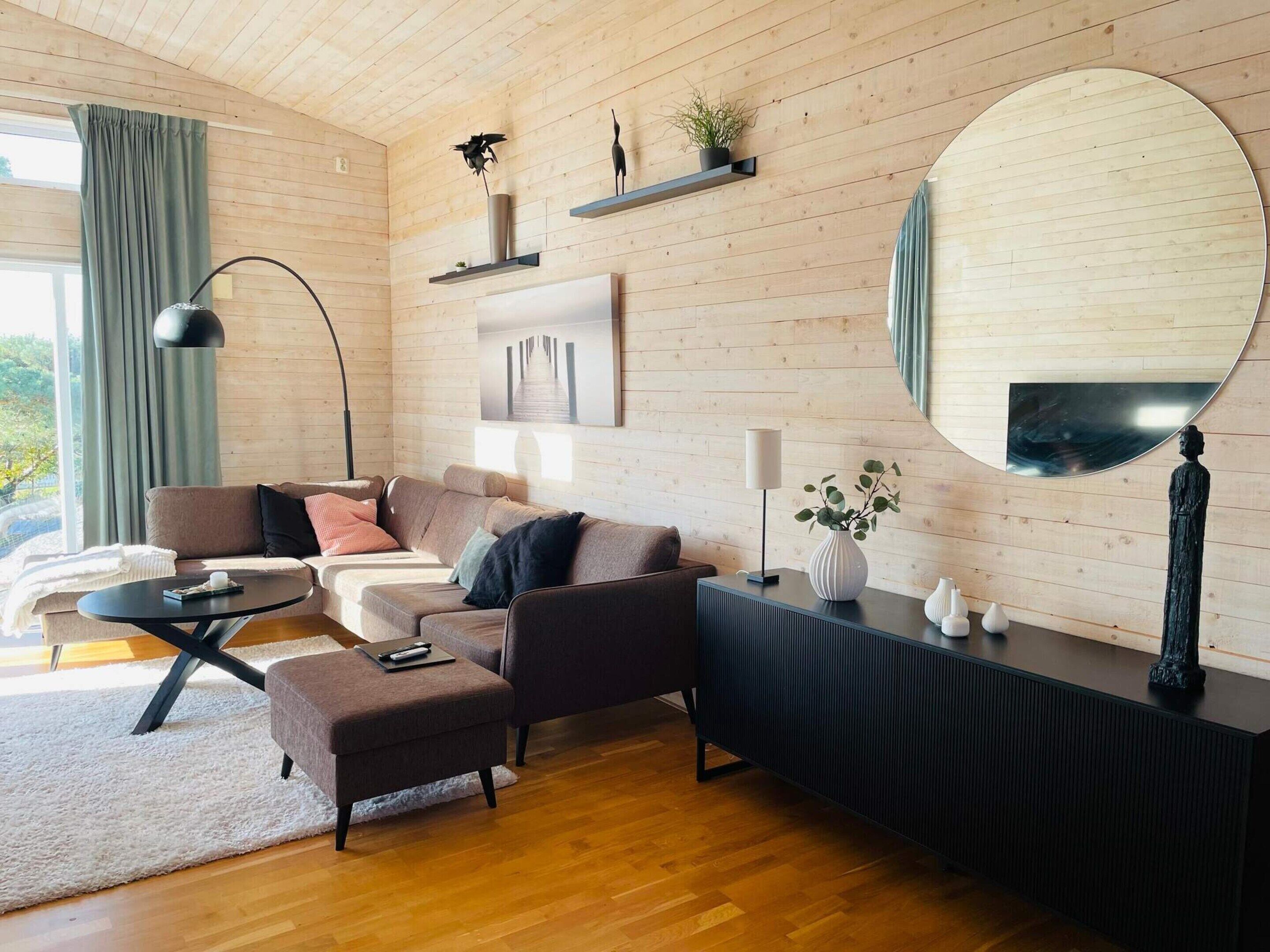 A modern living room with a sofa, ottoman, coffee table, and a console table with decorative items.