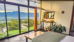 A bedroom with a large window, a bed, a wooden table, and a mirror. - Eco Suite 1-bedroom villa in awesome La Fortuna with AC (La Fortuna)