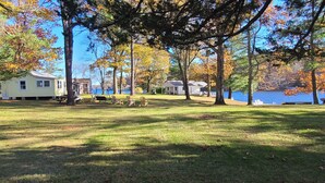 Une propriété située au bord d’un lac, dotée d’une pelouse verdoyante, de tables de pique-nique et d’une balançoire.