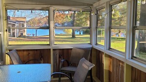 Une pièce d’angle avec vue sur un lac, des murs en bois, une table et deux chaises.