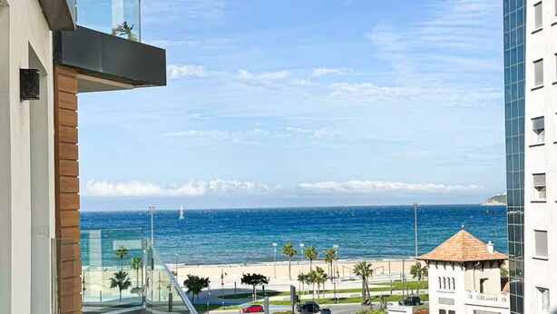 A high-rise building with a glass balcony overlooking a beach and ocean.