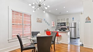 A modern kitchen with white cabinets, stainless steel appliances, and a dining area with a glass table and leather chairs.