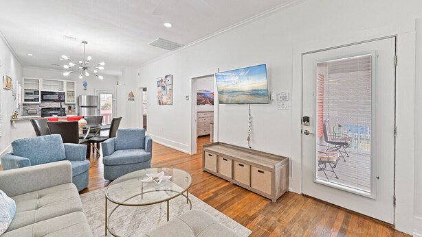 A modern living room with a dining area, kitchen, and a large TV.