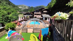 A pool area with a wooden fence, a wooden deck, and a mountain backdrop. - Holiday Home in Champagny Near Vanoise (Champagny-en-Vanoise)