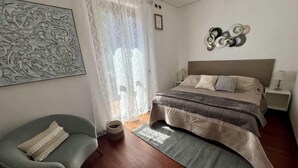 Une chambre à coucher moderne avec un grand lit, une chaise, une table de chevet et un élément décoratif mural.