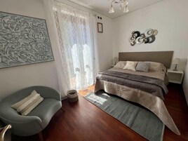 Un dormitorio moderno con una cama grande, una silla, una mesita de noche y un adorno en la pared.