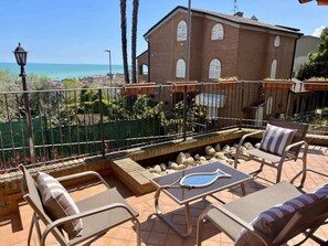 A terrace with outdoor furniture, a view of the sea, and a brick building in the background. - Elegant Villa With hot Tub, Views (Grottammare)
