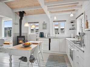 A modern kitchen with white cabinetry, a central island, a built-in stove, and pendant lighting.
