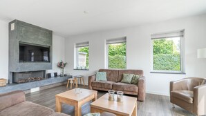 Ein modernes Wohnzimmer mit Kamin, einer Couch, einem Couchtisch und einem Ledersessel.