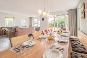 Un comedor moderno con una mesa de madera dispuesta para una comida, rodeada de sillas y un sofá.